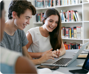 Students looking at laptop in library